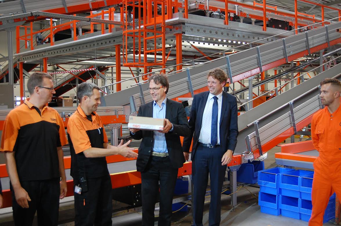 Voor de officiële opening van het nieuwe TNT depot in Eindhoven nam Staf Depla, Wethouder van Werk, Economie en Beroepsonderwijs, afgelopen vrijdag het eerste pakket in ontvangst van medewerkers van TNT Benelux. Managing Director TNT Benelux Erik Uljee (rechts) kijkt toe.