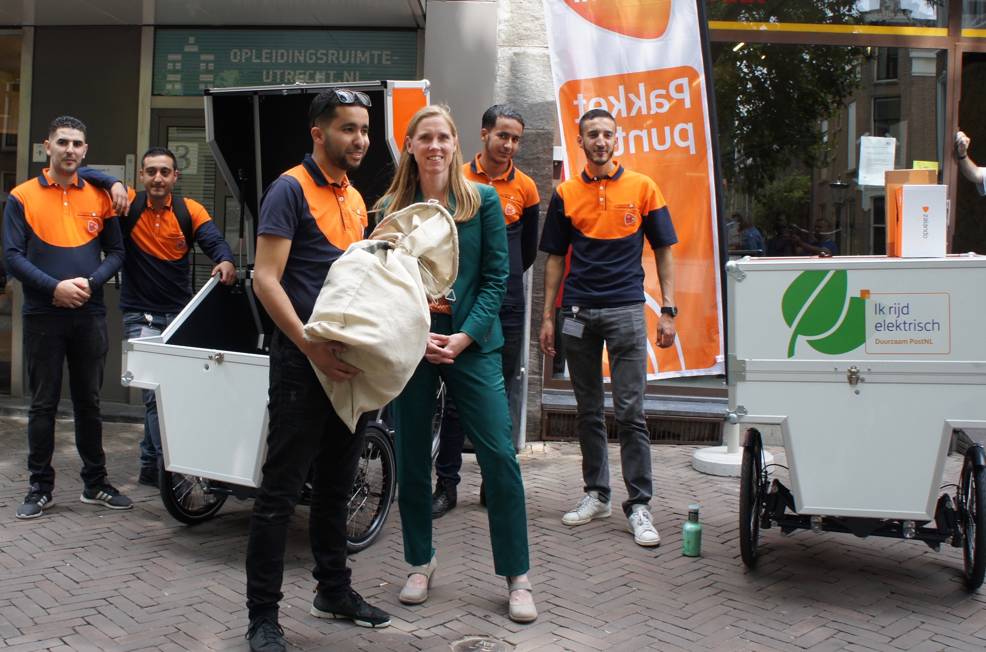 De Utrechtse wethouder Lot van Hooijdonk (rechts) gaf woensdag het startsein van de pilot waarbij PostNL een fietsenstalling in het centrum van de domstad onder andere fungeert als afhaalpunt voor pakketten.
