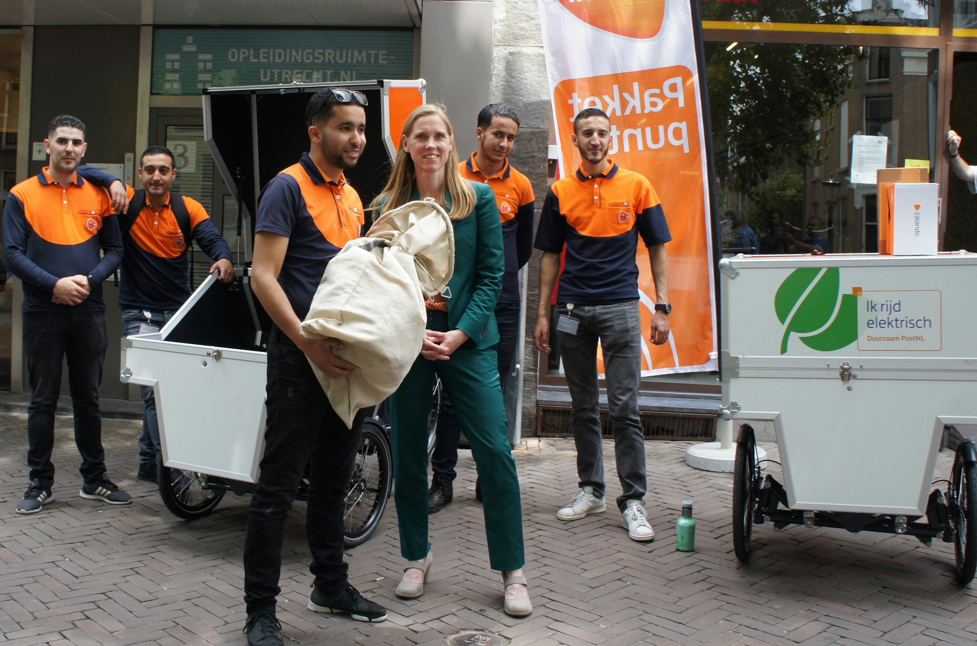 De Utrechtse wethouder Lot van Hooijdonk (rechts) gaf woensdag het startsein van de pilot waarbij PostNL een fietsenstalling in het centrum van de domstad onder andere fungeert als afhaalpunt voor pakketten.