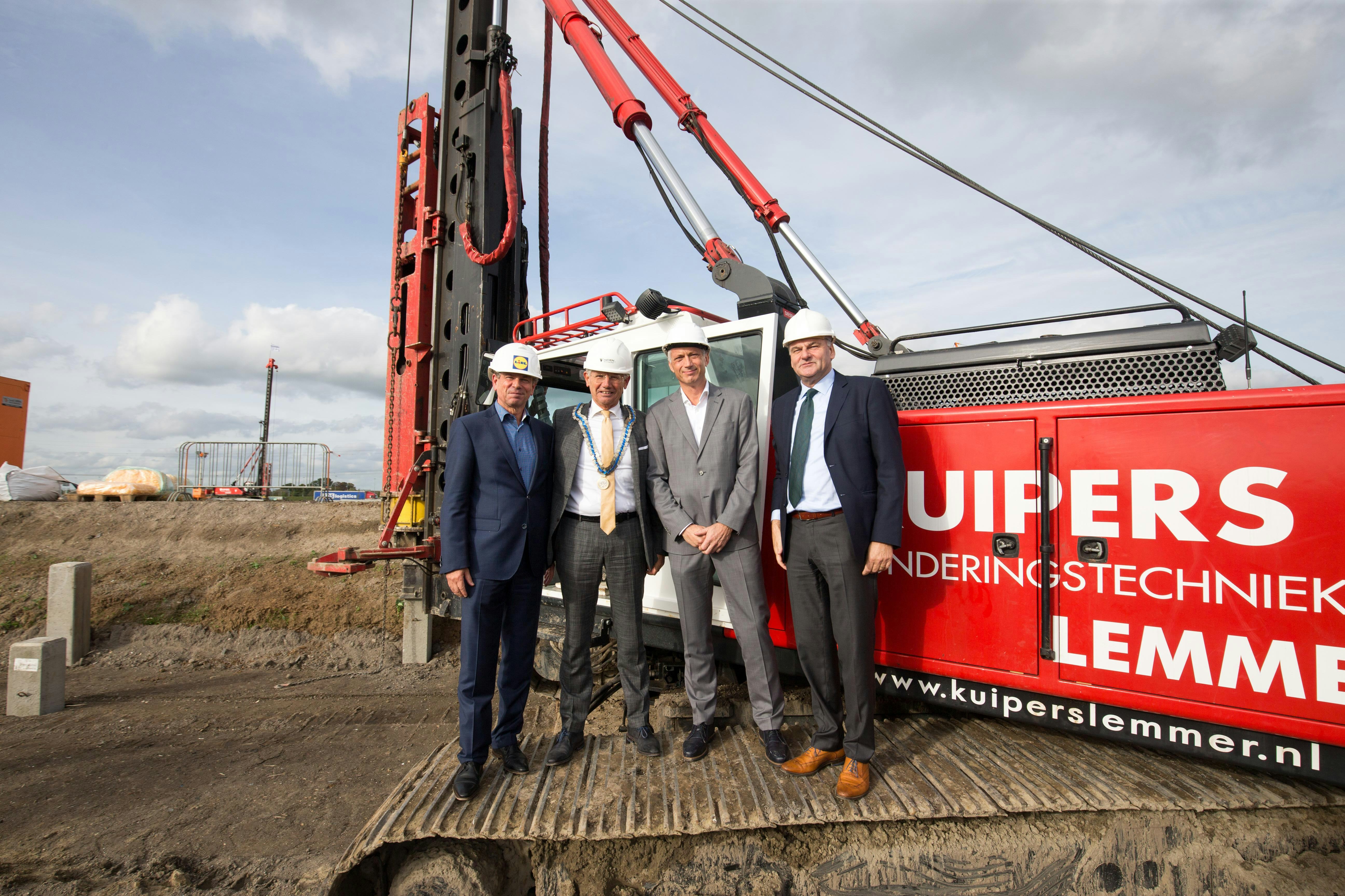 Burgemeester Toon van Asseldonk van de gemeente Overbetuwe, gedeputeerde Michiel Scheffer van de provincie Gelderland, directeur Centrale Diensten van Lidl Harm van Oorschot en regiodirecteur Peter Scholtens van Lidl Nederland, sloegen afgelopen donderdag de eerste paal voor een nieuw distributiecentrum in Oosterhout.