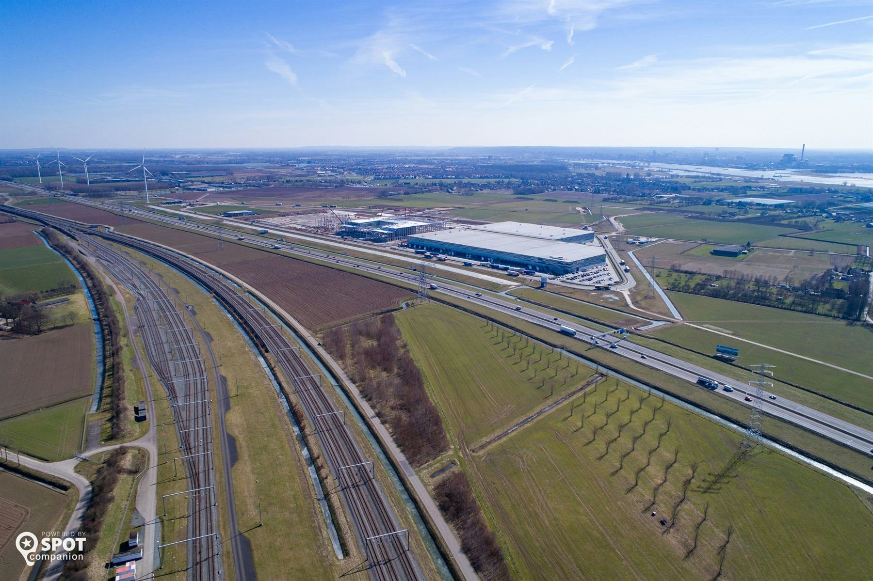 De Railterminal Gelderland moet gebouwd worden langs de Betuweroute, linksonder op de foto. Parallel aan de spoorlijn loopt de A15, met rechts ernaast bedrijventerrein Park15 waar inmiddels Nabuurs is gevestigd met een groot dc. Ook Lidl neemt binnenkort een groot dc op dit bedrijventerrein in gebruik.