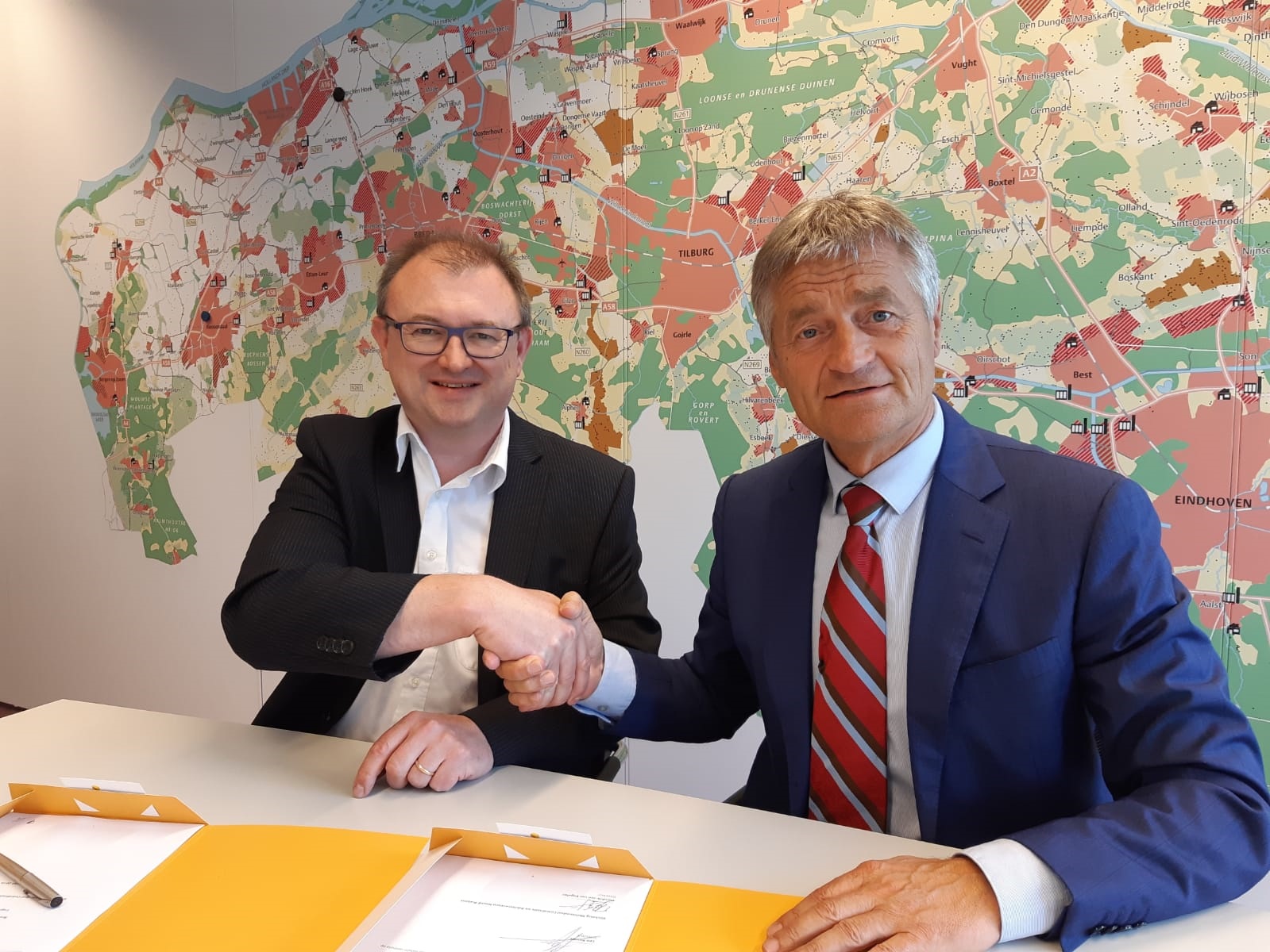 Hendrik-Jan van Engelen van MCA Brabant (links) en Leo Kemps van Logistics Community Brabant (LCB) schudden elkaar de hand na het ondertekenen van de overeenkomst waarin is afgesproken dat beiden organisaties nauw met elkaar gaan samenwerken bij het stimuleren van multimodaal transport in Brabant.