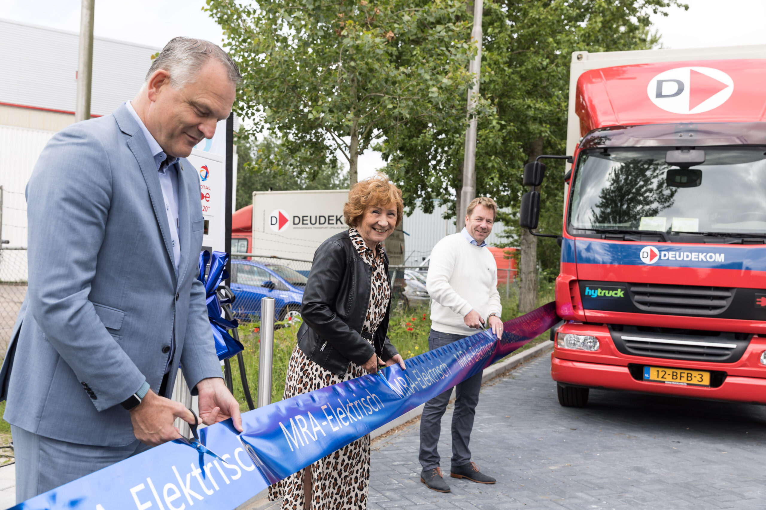 Gerard Slegers (vicevoorzitter Vervoerregio), Rineke Korrel (wethouder gemeente Ouder-Amstel) en Jan van Deudekom (eigenaar) openen officieel het laadstation. Fotograaf: Marit van den Berg Photography