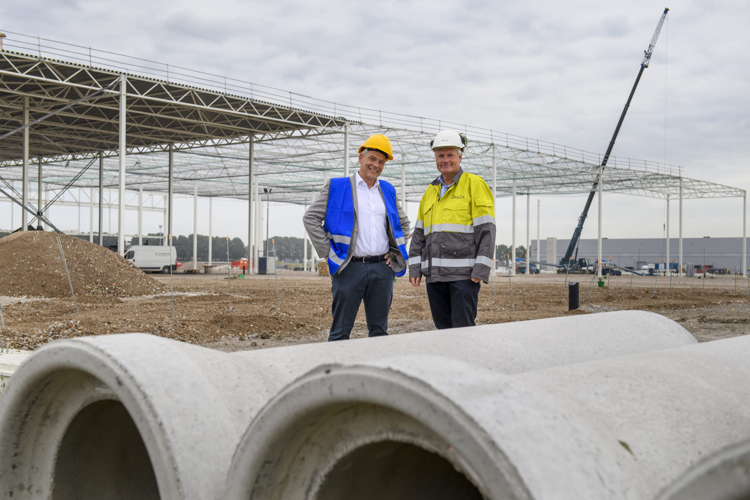 Tim Beckmann (rechts), ceo Intospace, en Joulz-directeur Jan Verheijen voor het in aanbouw zijnde distributiecentrum op Schiphol Trade Port dat geheel zelfvoorzienend wordt in zijn eigen energiebehoefte.
