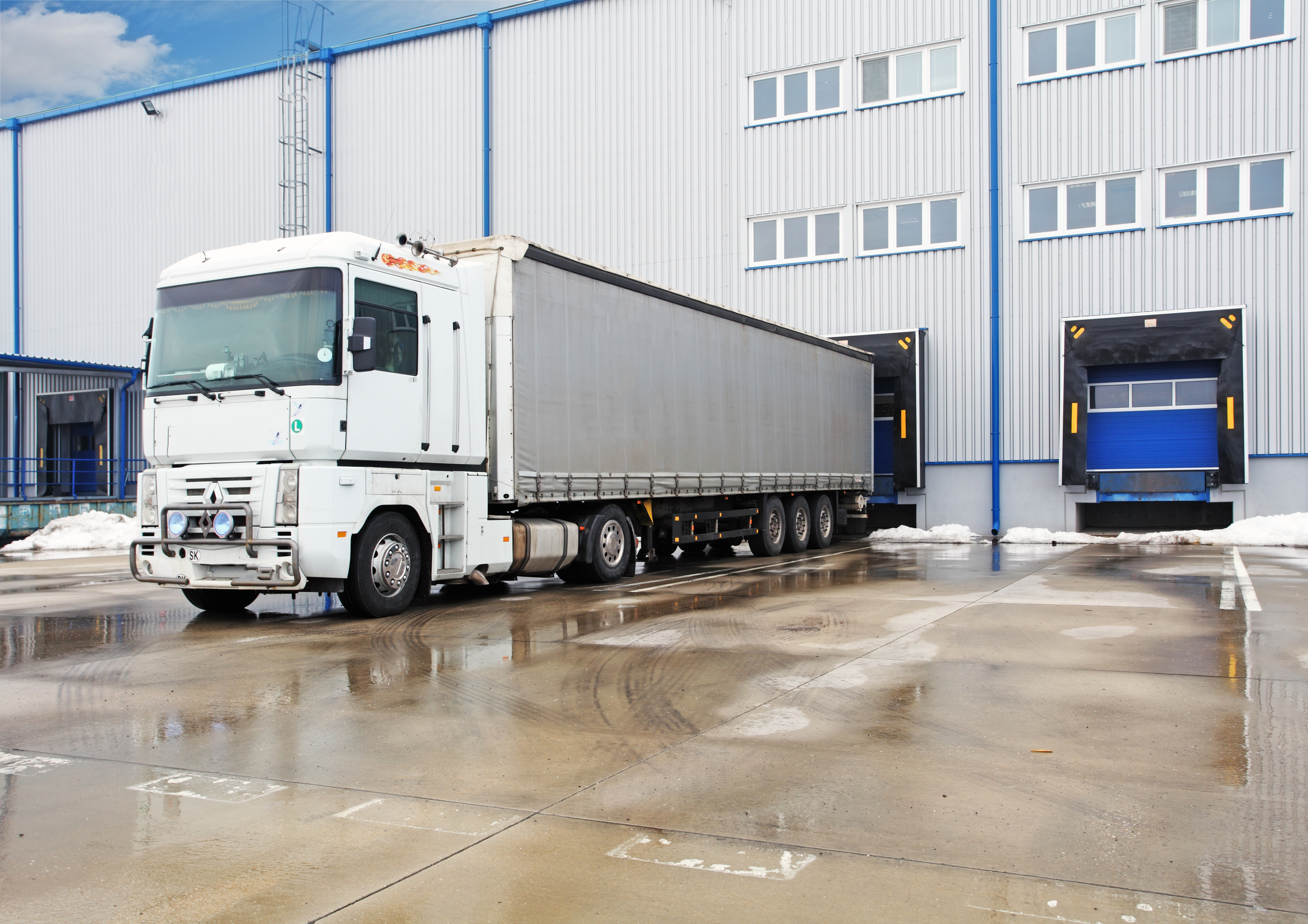 Unloading big container trucks at warehouse building