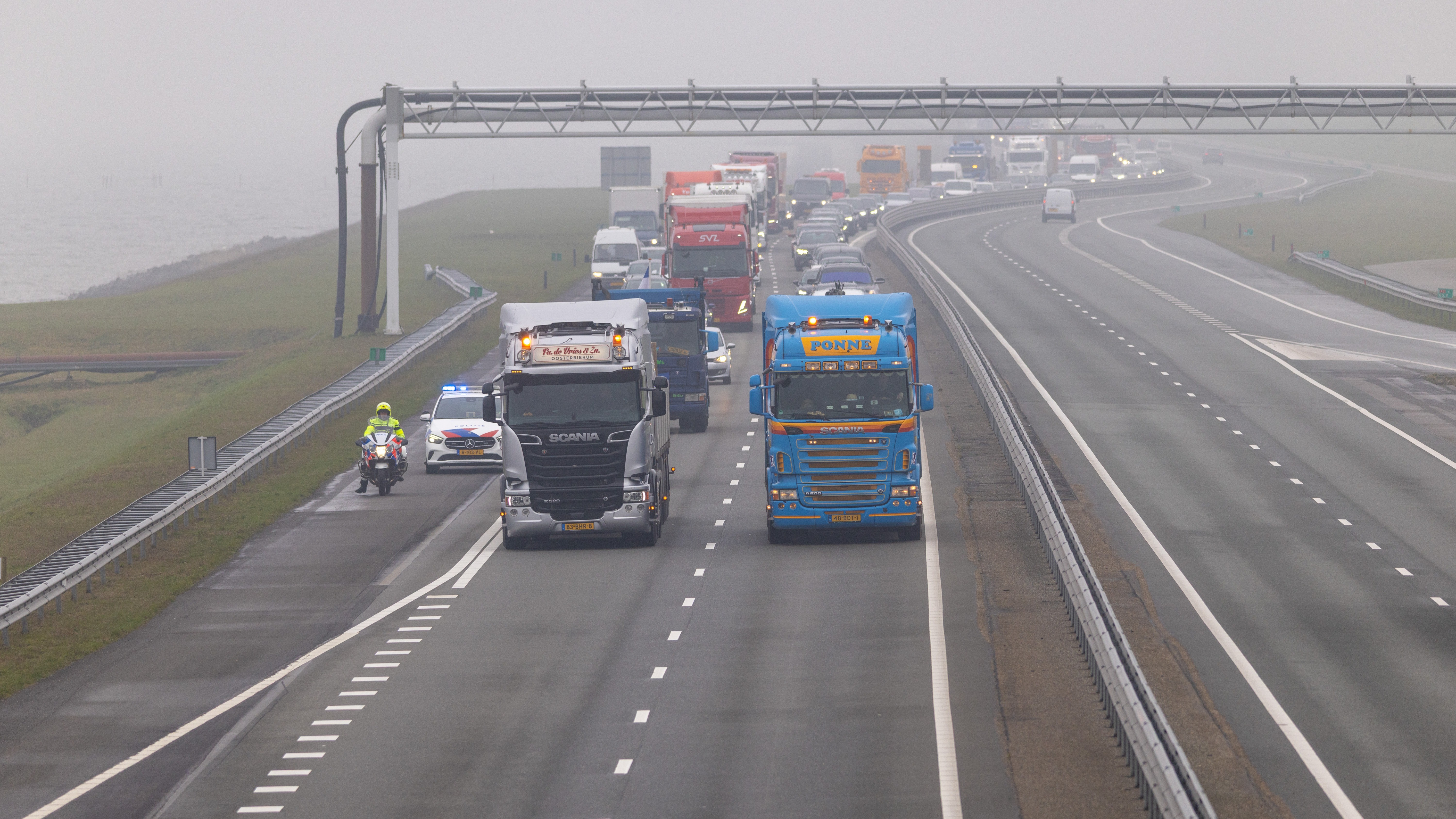Een groep vrachtwagenchauffeurs voert actie tegen de hoge brandstofprijzen door met meerdere trucks naast elkaar in langzaam tempo over de Afsluitdijk te rijden. Foto: Jaring Rispens / ANP