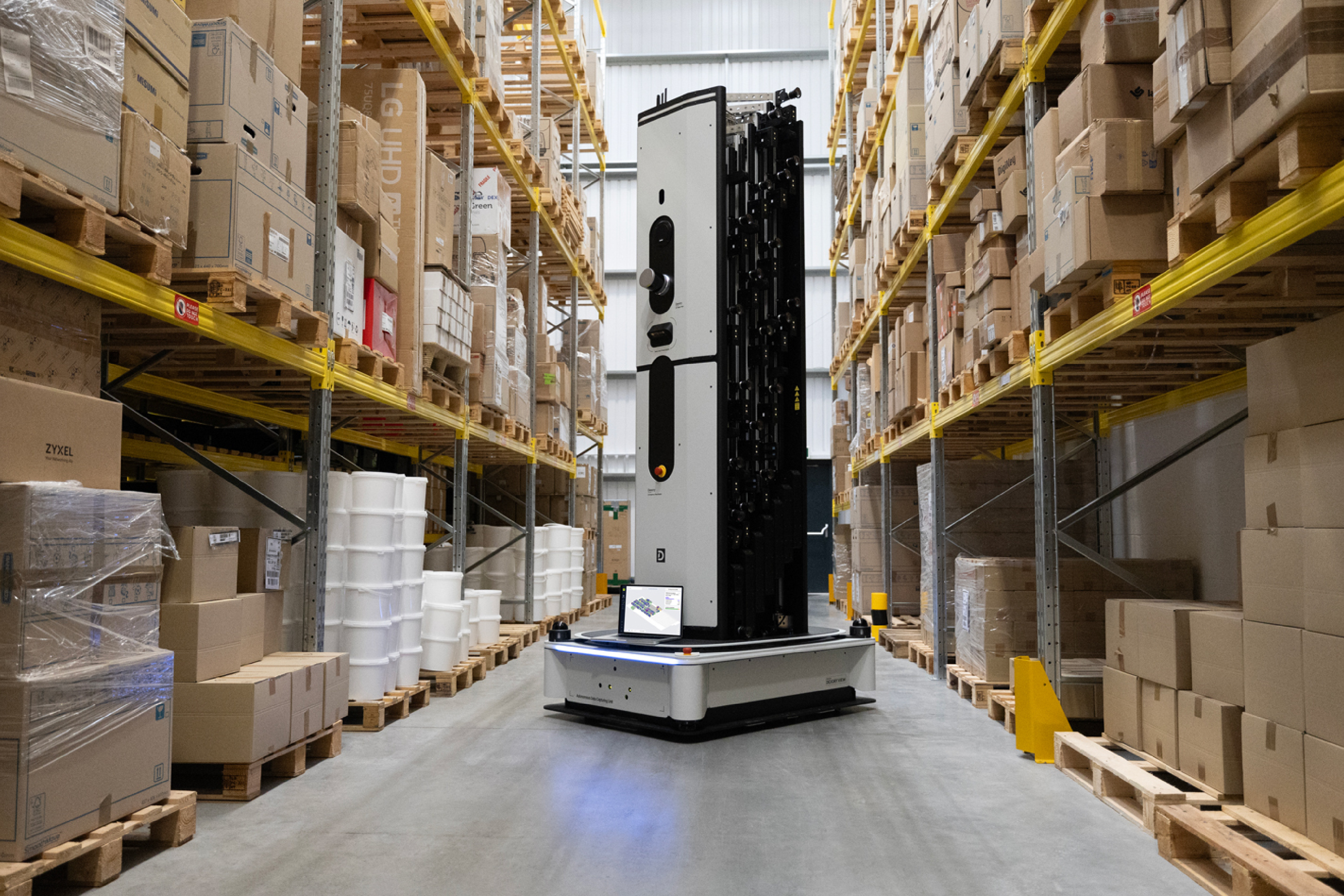 Een autonome robot van Dexory rijdt door de gangpaden van een magazijn en legt onderweg continu de voorraad vast, zonder dat medewerkers repetitieve controles hoeven uit te voeren.