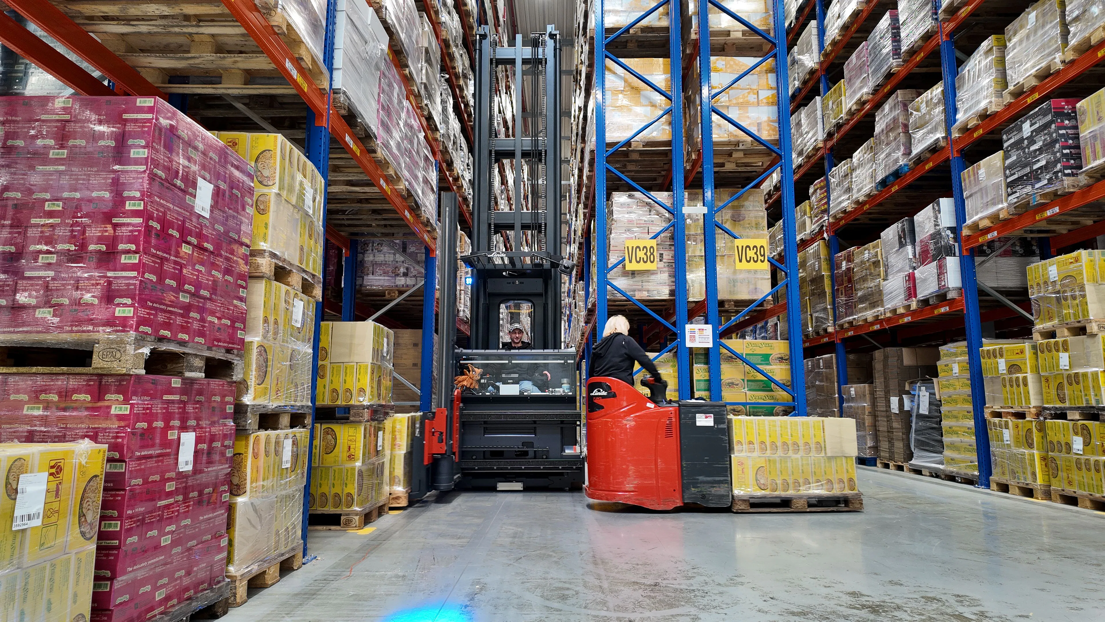 Een Linde VNA-combitruck en een stapelaar aan het werk in de smalle gangen van het nieuwe warehouse.