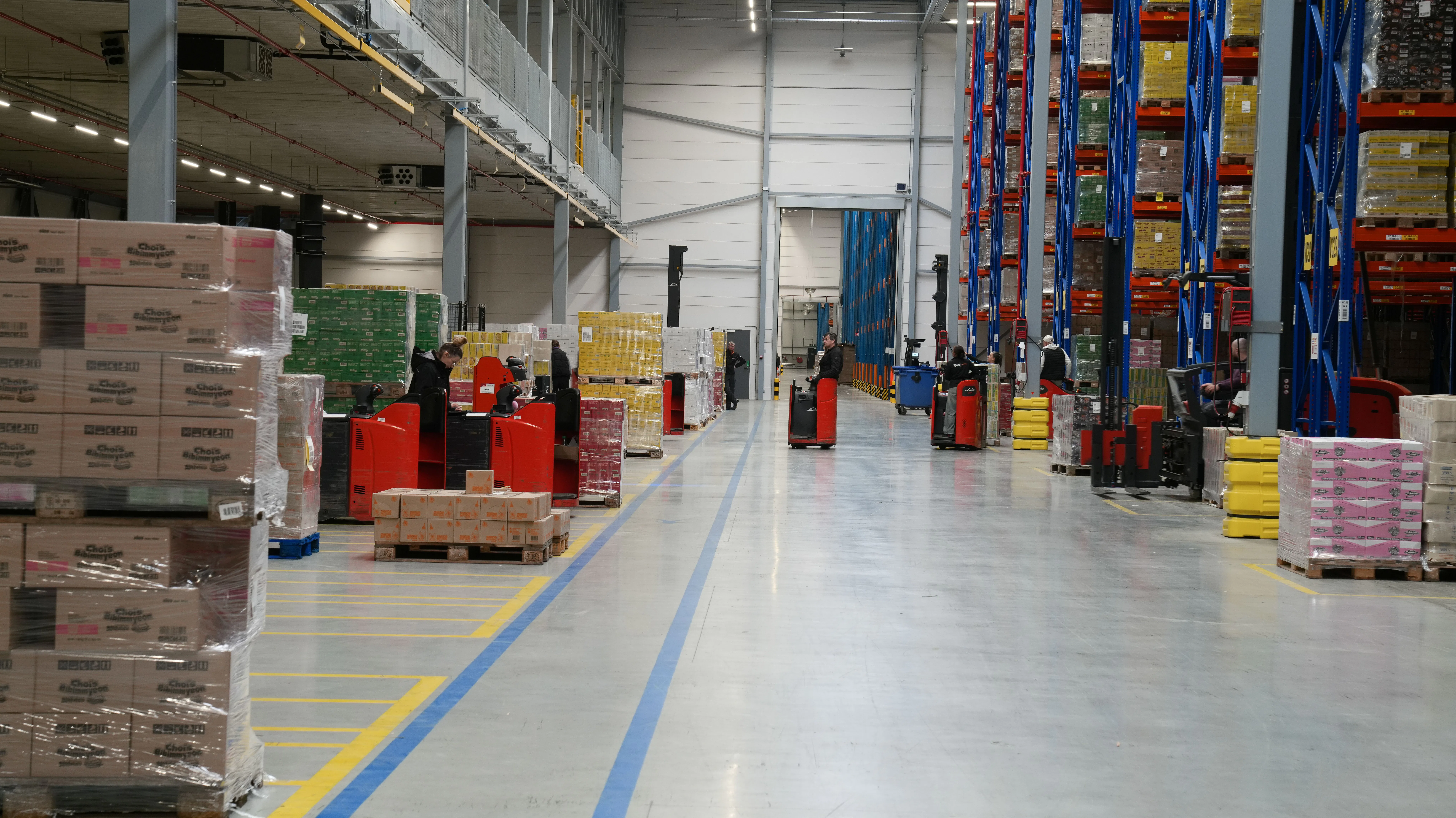 Overzicht van de werkvloer in het nieuwe warehouse: Linde-stapelaars en -pallettrucks bij de hoge magazijnstellingen.