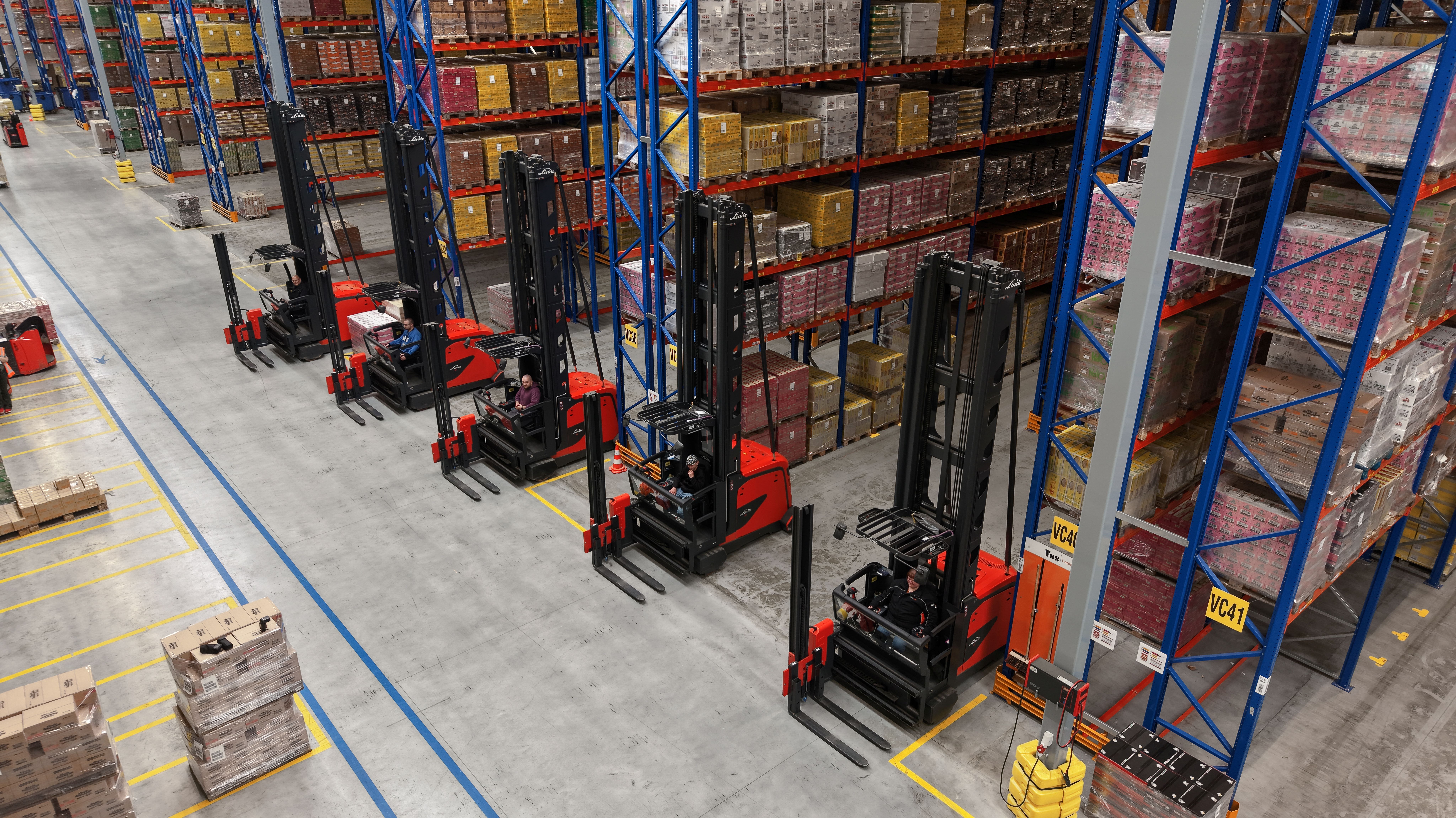 De vijf Linde VNA-combitrucks die Motrac leverde, opgesteld voor de stellingen in het nieuwe smallegangenmagazijn van Vos Logistics in Oss.